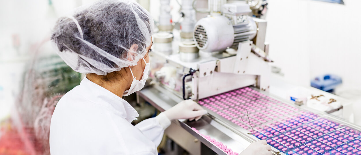 Person working with selection of pink pills on a production line