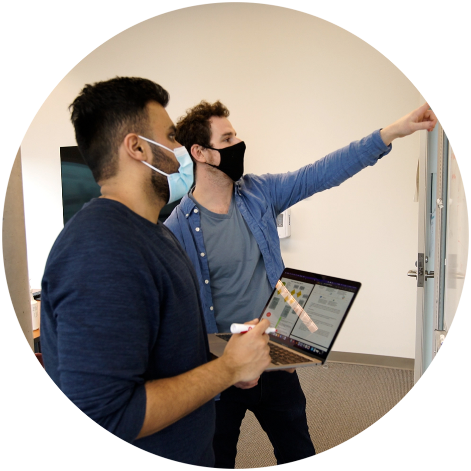 Two students reviewing code on whiteboard