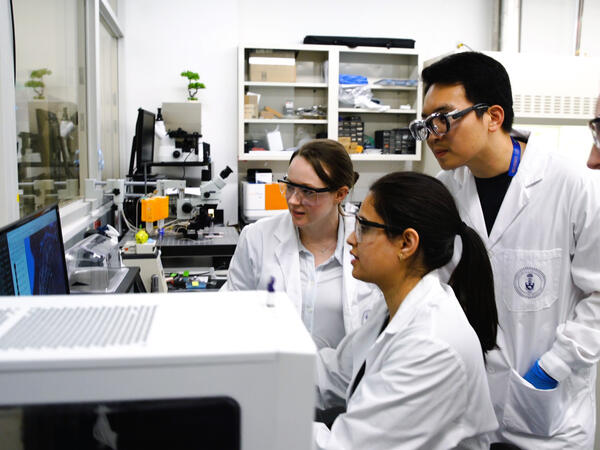 Graduate students analyzing a screen in a group inside a laboratory