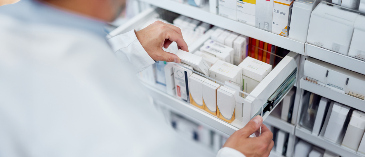 Pharmacist grabbing medication from a drawer in a pharmacy